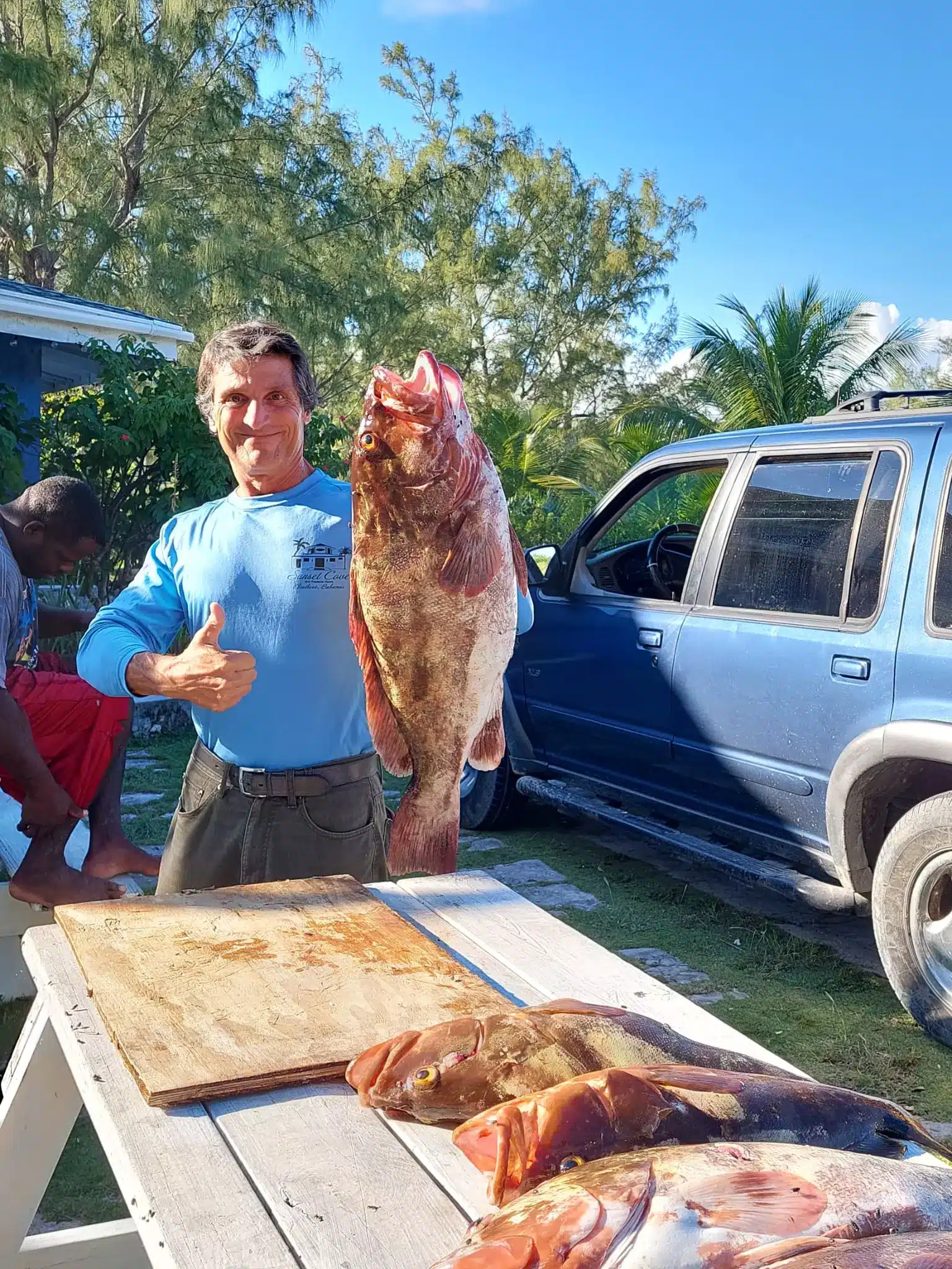 Pescatore che mostra una cernia appena pescata alle Bahamas