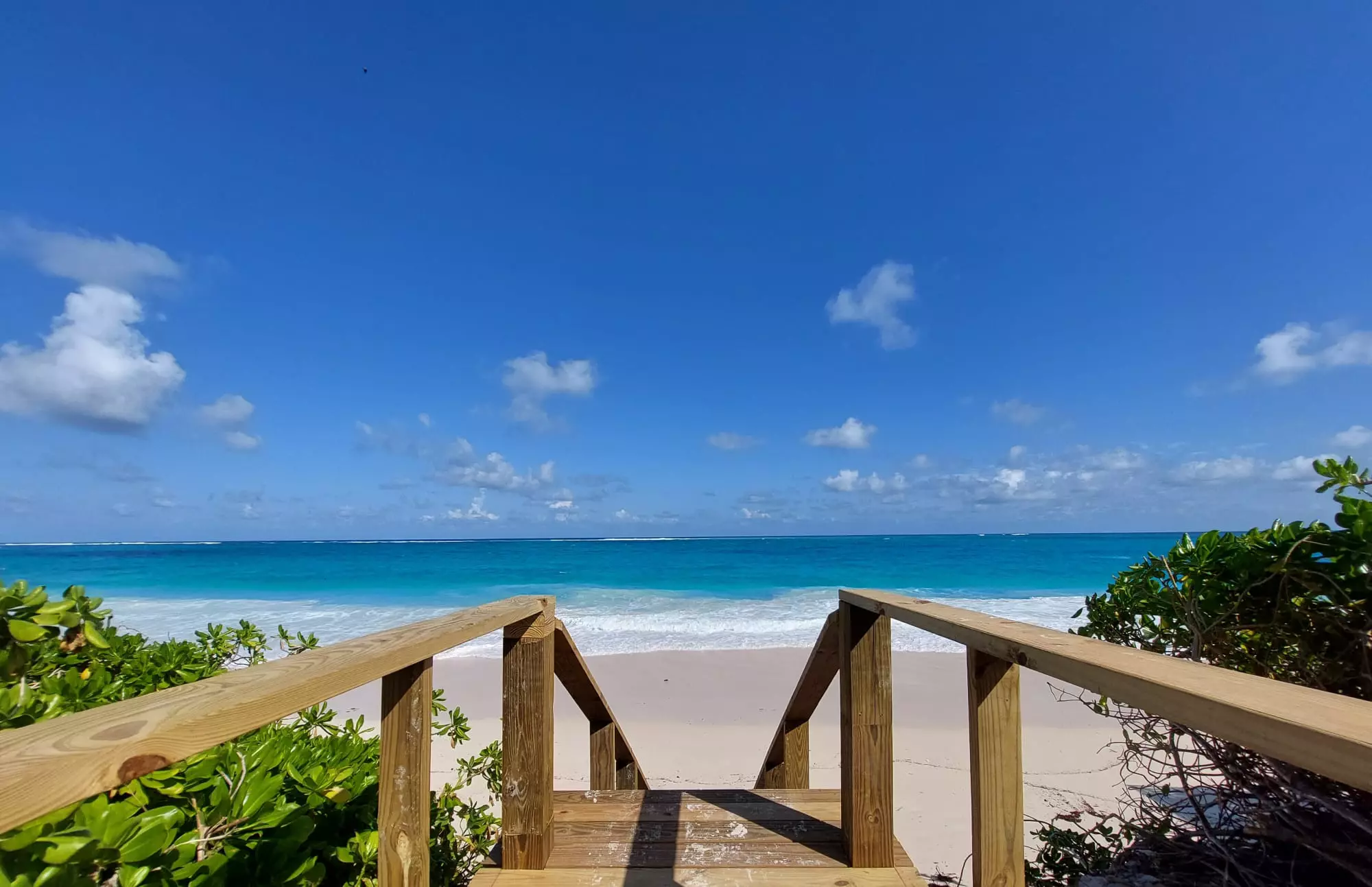 Passerella di legno che scende su una spiaggia bianca con mare turchese alle Bahamas
