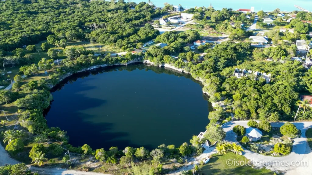 Blue hole circondato da case e alberi visto dal drone a Eleuthera, Bahamas