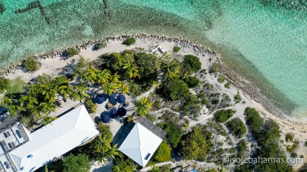 Piccolo resort con ombrelloni blu e tetti bianchi sul mare a Eleuthera, visto dal drone