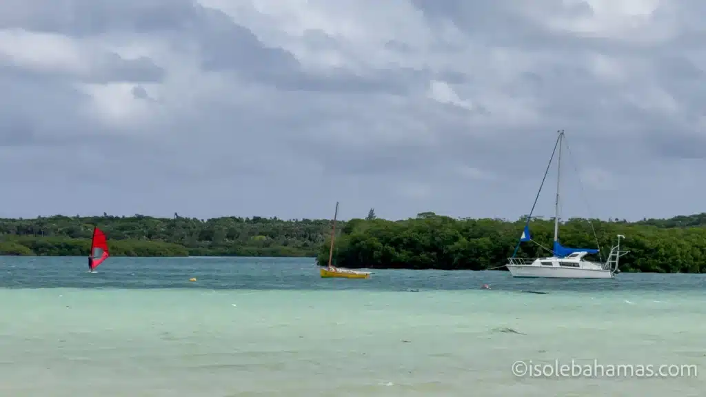 Windsurf e barche a vela in una baia delle Bahamas sotto un cielo nuvoloso